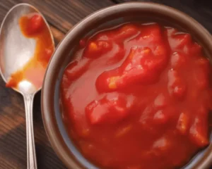 A beginner's guide to canning tomatoes, featuring jars and fresh tomatoes.