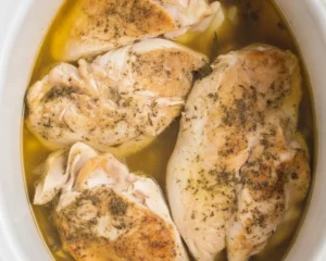 Juicy slow cooked chicken breasts in a crockpot with flavorful herbs and sauce.