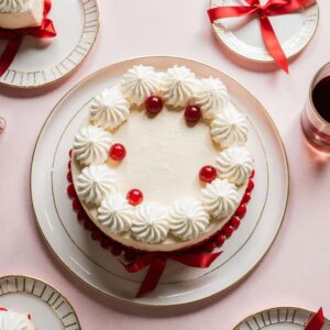 Simple Lambeth-style birthday cake with white ruffles and red bows.
