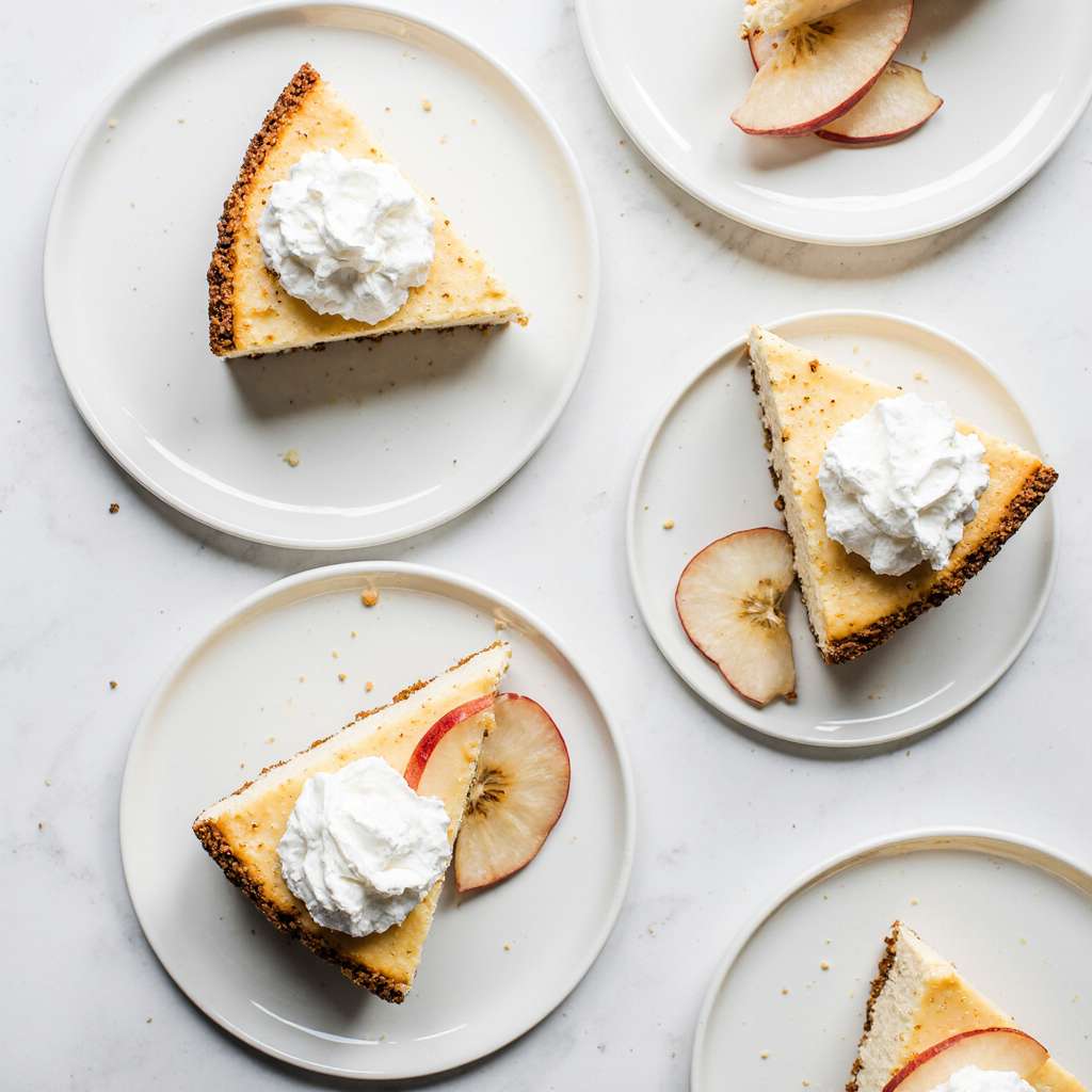 Slices of apple crumble cheesecake served with whipped cream.