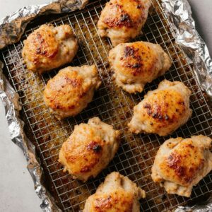 Crispy baked chicken thighs on wire rack, golden brown.