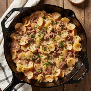 Creamy Parmesan garlic beef bowtie pasta in skillet with parsley garnish.