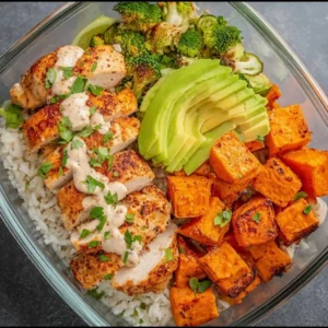 Healthy chicken and sweet potato rice bowl with colorful vegetables and toppings.