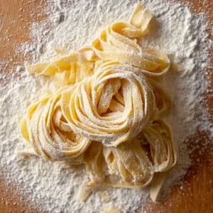 Homemade sourdough pasta with fresh ingredients on a wooden surface.