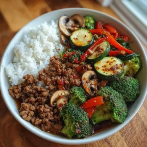 Spicy ground beef stir-fry bowl topped with garlic vegetables and served with rice