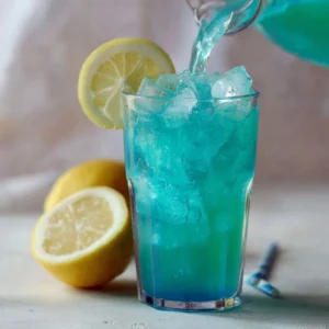 Glass of blue raspberry lemonade with fresh raspberries and lemon slices