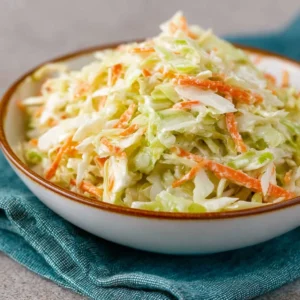 Bowl of sweet coleslaw with fresh vegetables and dressing