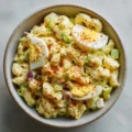Delicious deviled egg macaroni salad served in a bowl with a sprinkle of herbs.