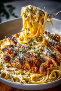 A plate of creamy Chicken Alfredo pasta garnished with parsley.