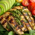 Pesto grilled chicken avocado salad garnished with fresh herbs and tomatoes